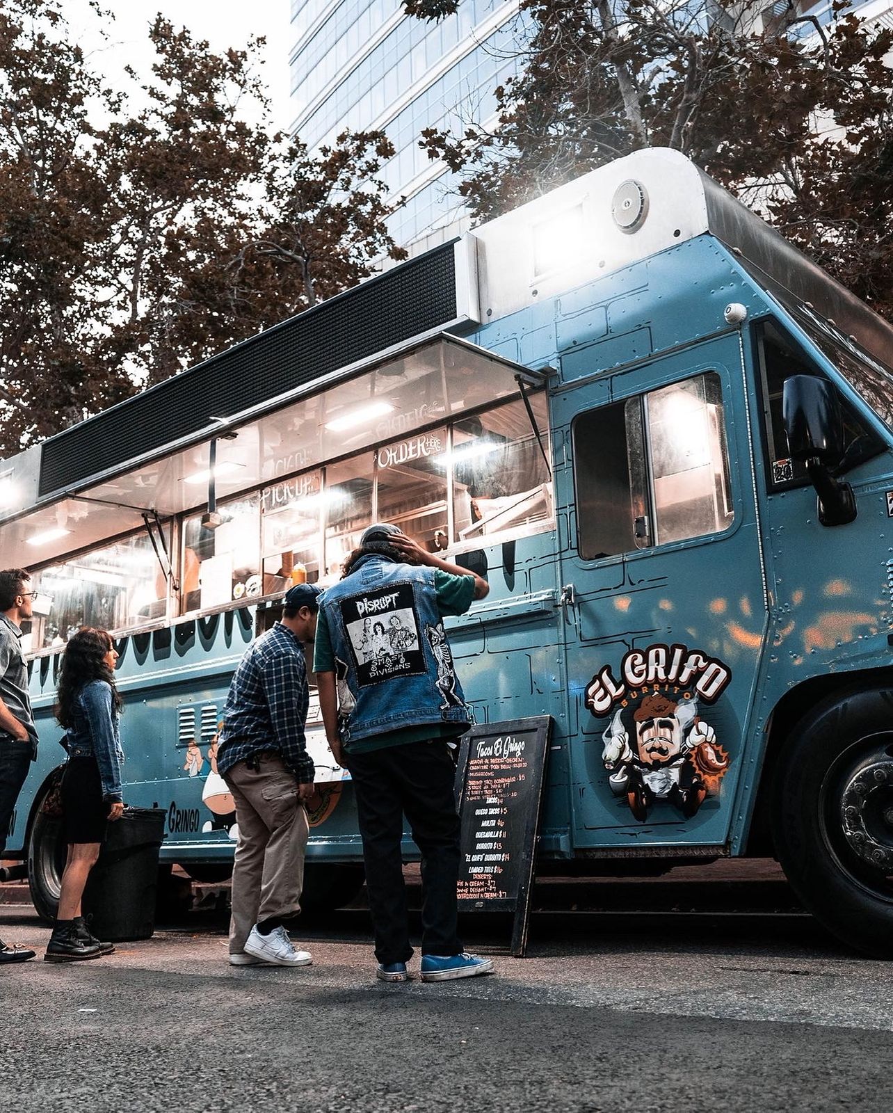 The Tacos El Gringo truck lit up at night with customers ordering