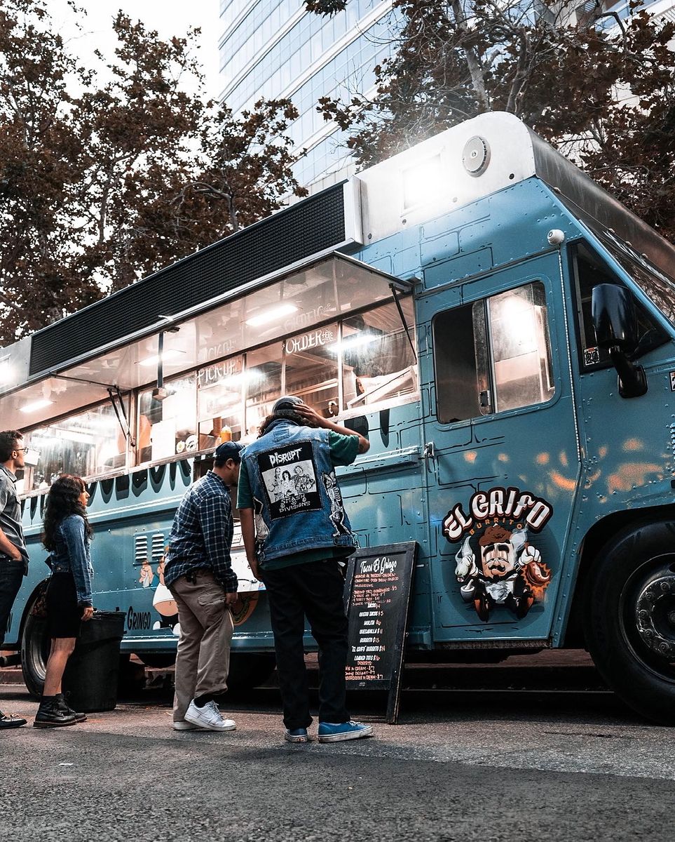 The Tacos El Gringo truck lit up at night with customers ordering